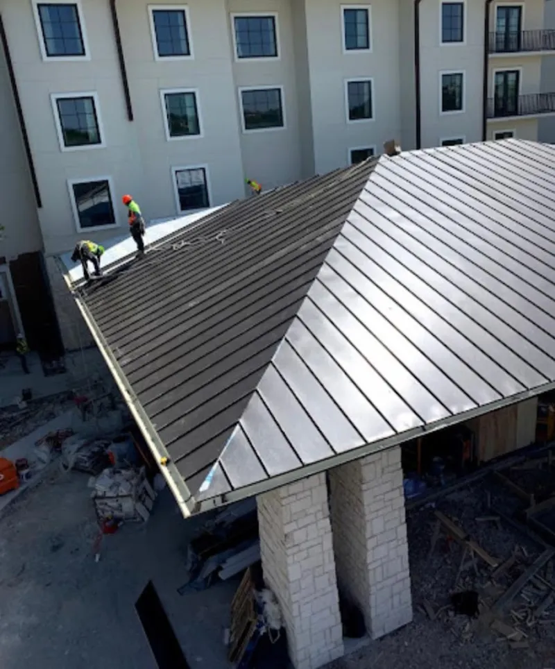 Crew installing standing seam metal roof panels on a commercial project in Maynard
